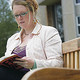A student reading a catalogue on a bench