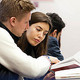 Two students, male and female, reading a textbook